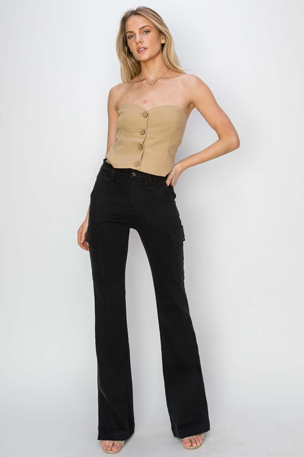 Model wearing high-rise side slit cargo bootcut jeans by Risen Jeans with a beige strapless top, showcasing a trendy and versatile outfit.