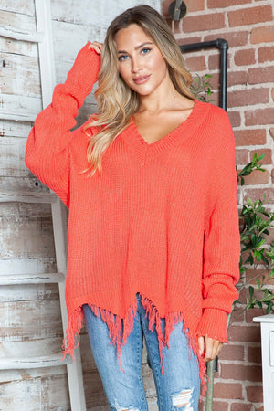 Woman wearing Bella Road frayed hem dropped shoulder sweater in vibrant orange, pairing it with casual blue jeans.