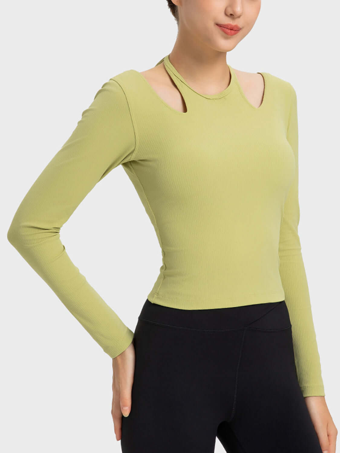 Stylish woman wearing a green Millennia halter neck long sleeve sporty top, perfect for workouts and staying comfortable.