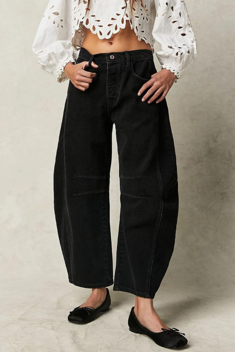 Woman wearing wide leg jeans with pockets and a white crop top with eyelet details.