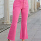 Bella Road raw hem high waist bootcut jeans in pink with front pockets, styled with white sandals and a crop top.