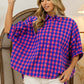 Woman wearing Plaid Button Up Dolman Sleeve Shirt with blue and pink checkered pattern and white shorts standing indoors