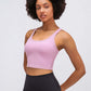 Stylish model wearing Millennia Racerback Sports Bra in soft pink, perfect for yoga and activewear fashion.