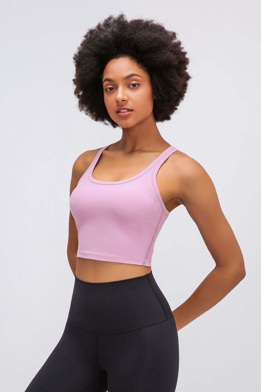 Stylish model wearing Millennia Racerback Sports Bra in soft pink, perfect for yoga and activewear fashion.