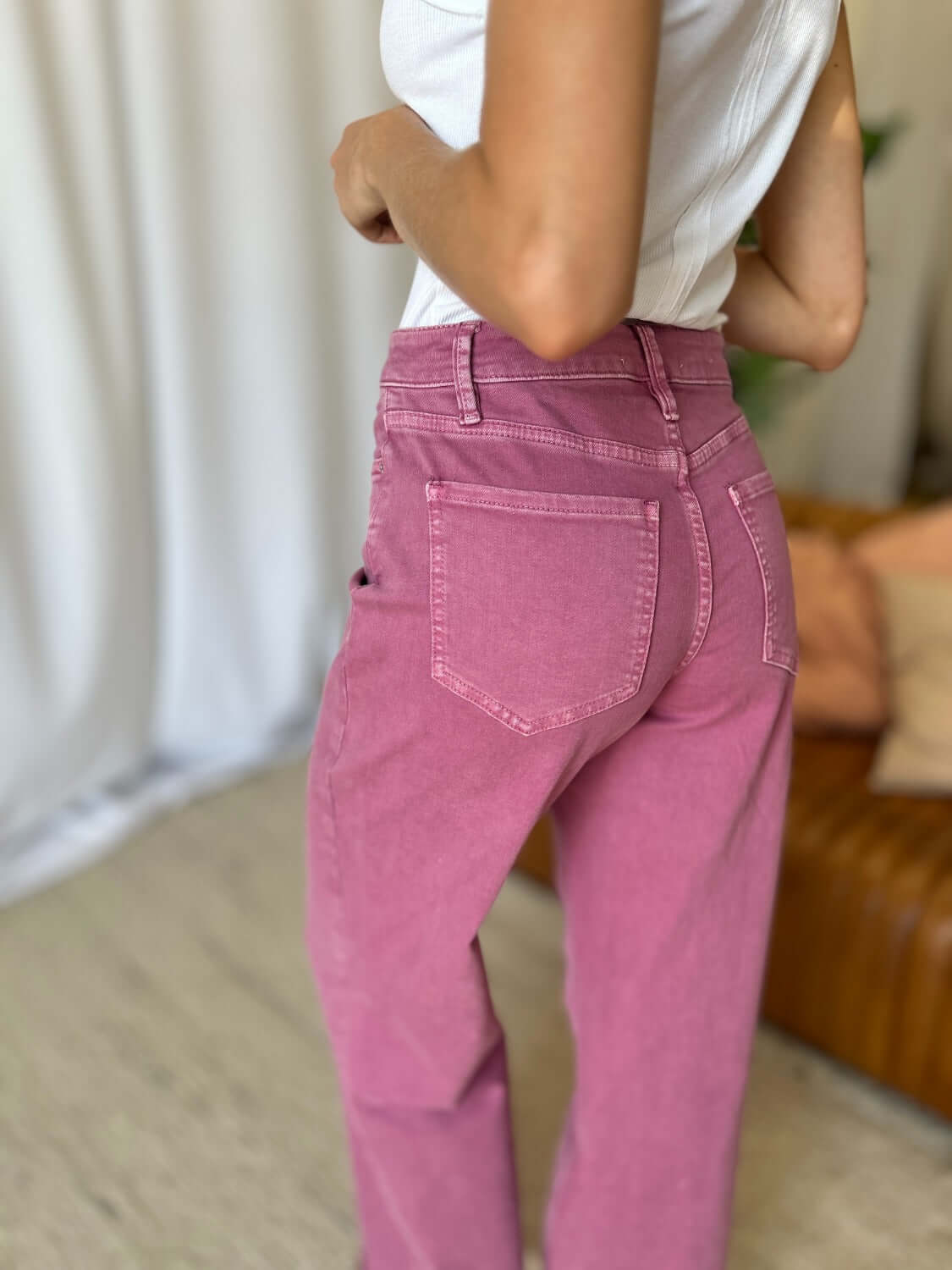 Woman wearing RFM full size high rise garment dye wide leg jeans in rich pink color, showcasing back pocket detail and high-waist fit.