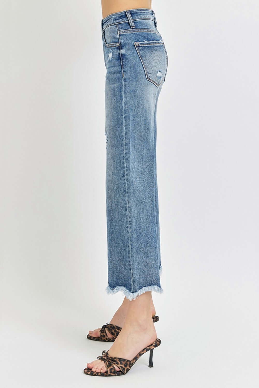 Side view of Risen Jeans High Rise Cropped Flare Jeans showing frayed hem and leopard print heels.