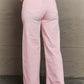 Model wearing Raelene High Waist Wide Leg Jeans in Light Pink by Risen Jeans, showcasing the flattering fit and stylish retro design.