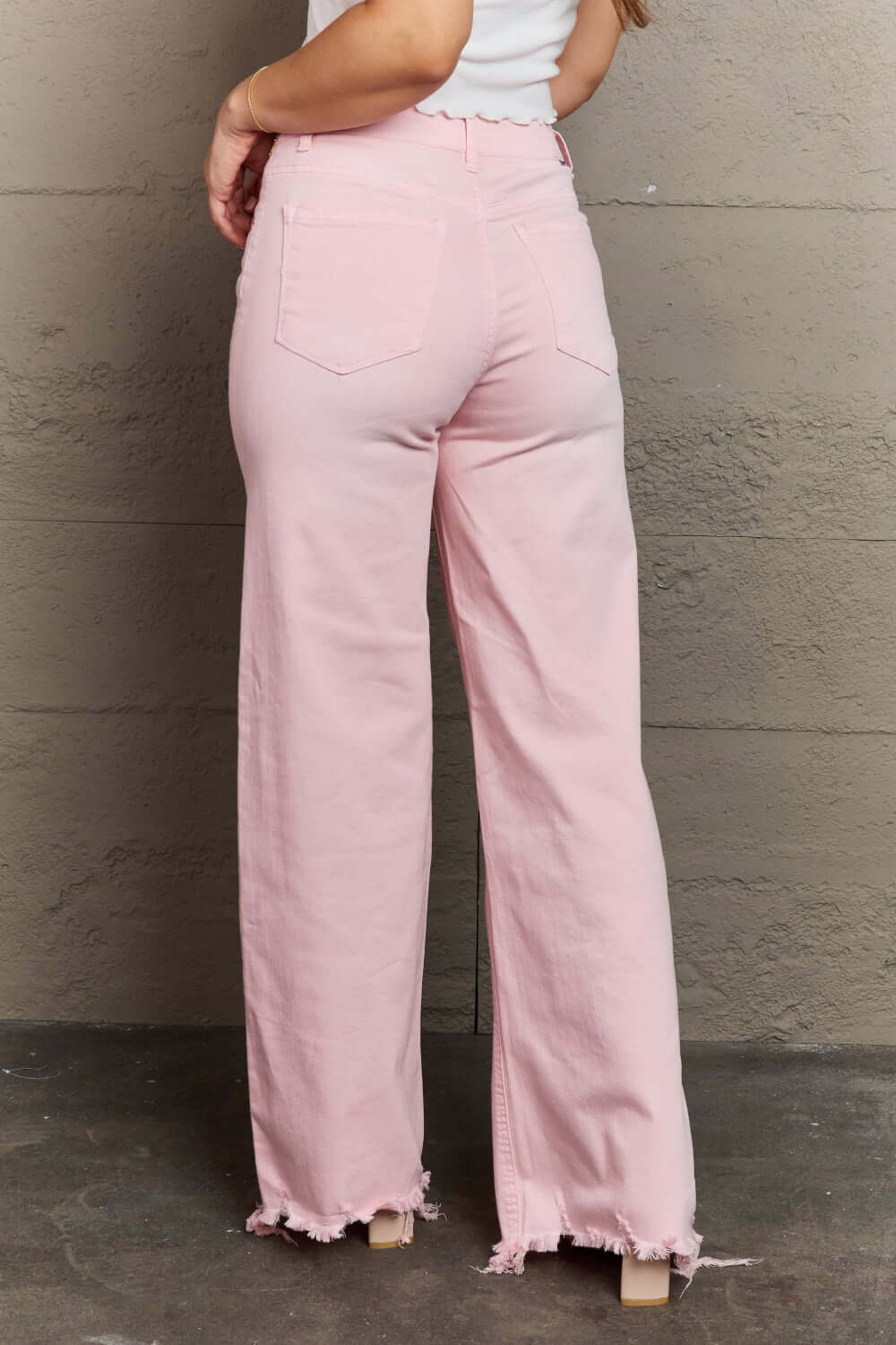 Model wearing Raelene High Waist Wide Leg Jeans in Light Pink by Risen Jeans, showcasing the flattering fit and stylish retro design.