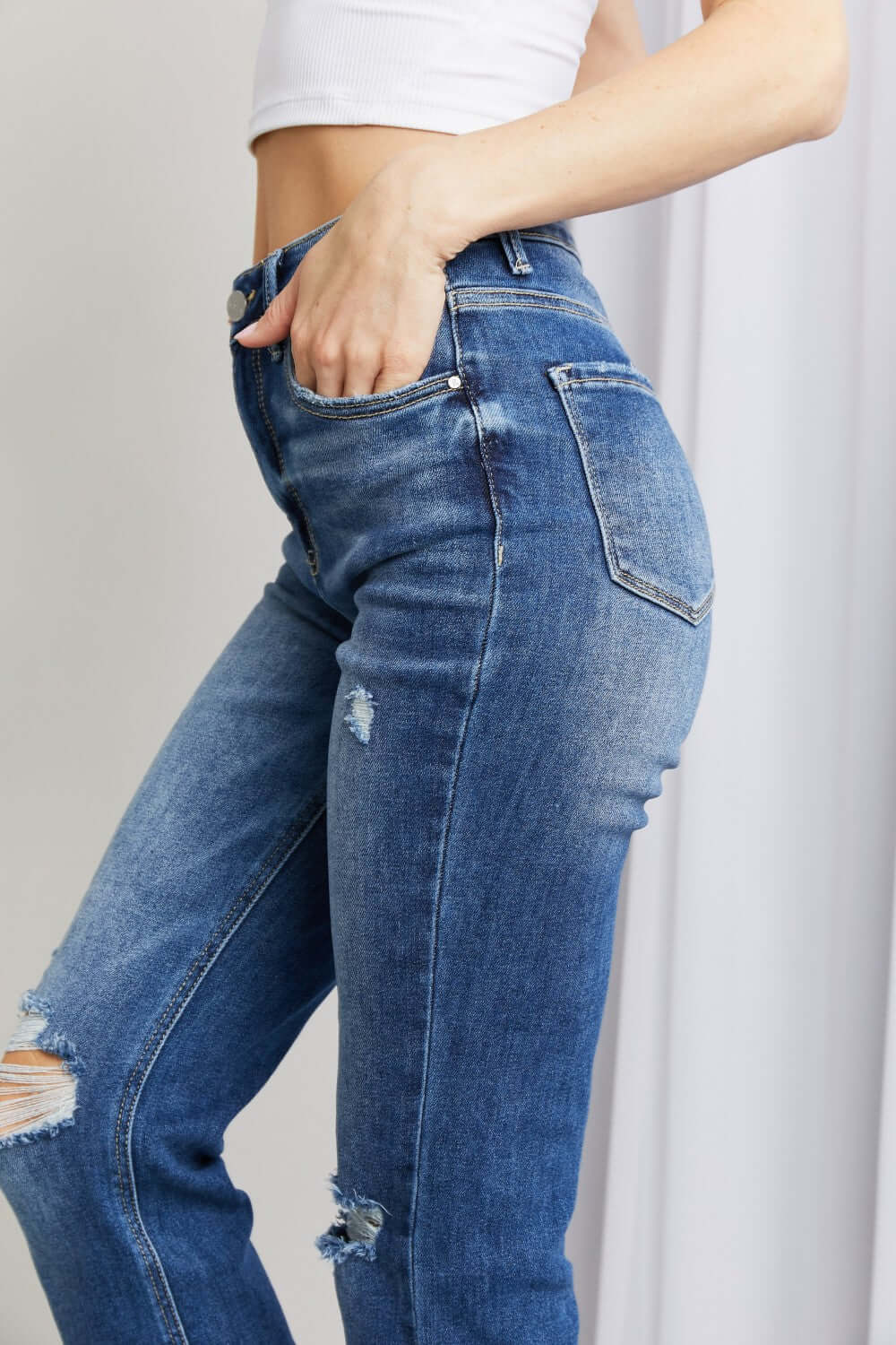 Stylish frayed hem distressed cropped jeans with pockets by Risen Jeans, featuring moderate stretch and raw hems for a casual, chic look.