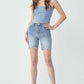 Model wearing high rise distressed denim shorts with raw hem and a blue crop top, perfect for an edgy urban look - Risen Jeans.