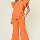 Woman wearing orange texture ruffle short sleeve top and drawstring wide leg pants set with pockets.