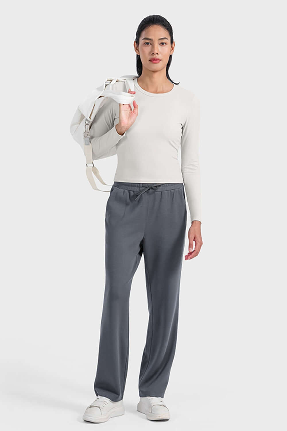 Stylish woman in a light long sleeve sports top and grey pants, ready for an active day or workout.