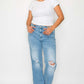 Woman in a white tee and distressed high rise straight jeans, showcasing a trendy casual look with confidence.