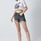 Woman wearing High Rise Distressed Denim Shorts by Risen Jeans and white graphic tee on white background