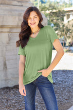 Woman wearing a green Basic Bae Bamboo Full Size V-Neck Short Sleeve T-Shirt standing outdoors