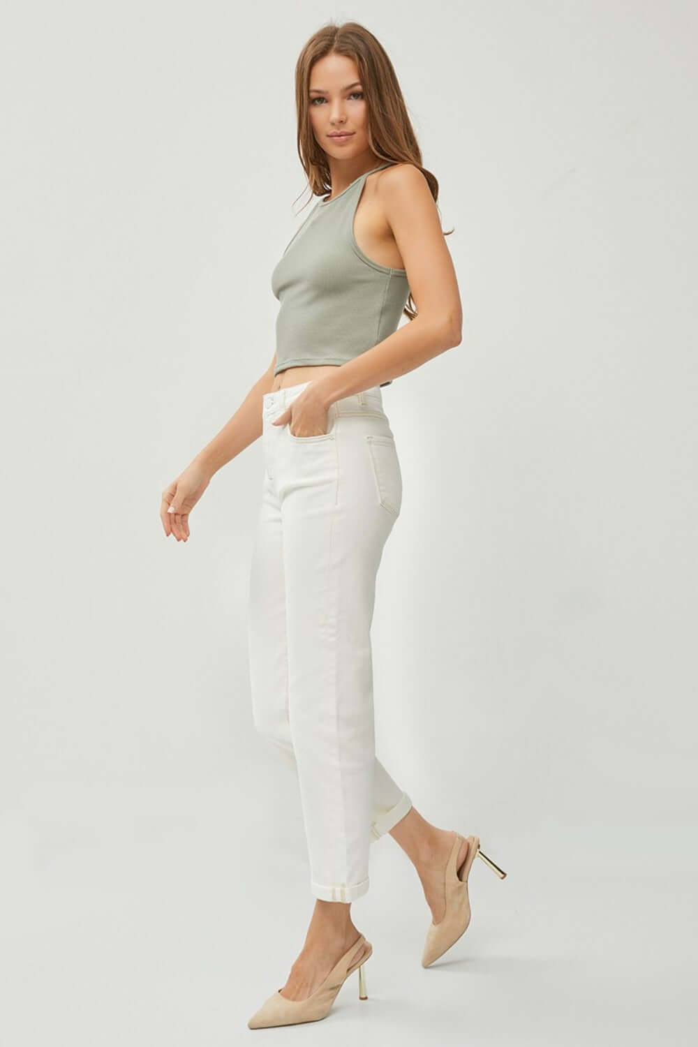 Model wearing RISEN Full Size High Waist Rolled Hem Straight Jeans in white with a casual green tank top and beige heels.