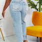 Back view of model wearing Allie 90's Dad Jean with distressed details and raw hem, light wash.