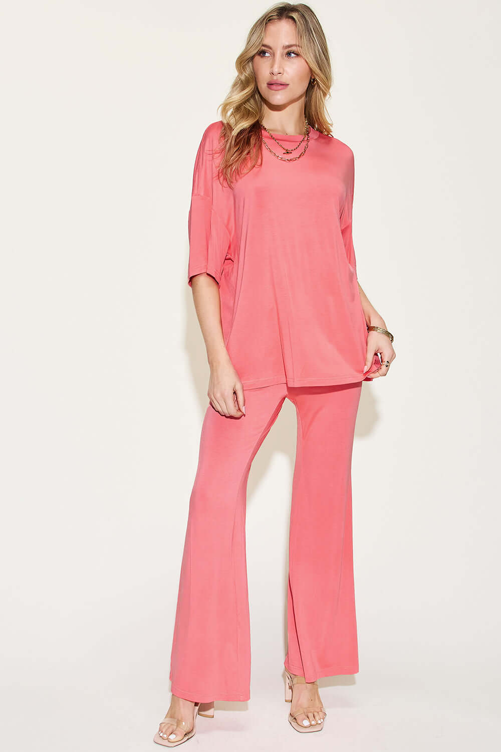 Woman wearing bamboo drop shoulder T-shirt and flare pants set in coral color, basic style, stretchy, two-piece outfit.