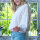 Woman in Hailey & Co rib and two-tone knit mixed top with denim shorts, standing by a sunlit window.