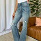 Woman wearing Judy Blue medium rise tummy control destroy flare jeans with distressed details and a white tank top.