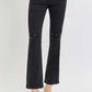 Black high-rise wide waistband ankle bootcut jeans with distressed detailing, styled with clear heels for a modern look.