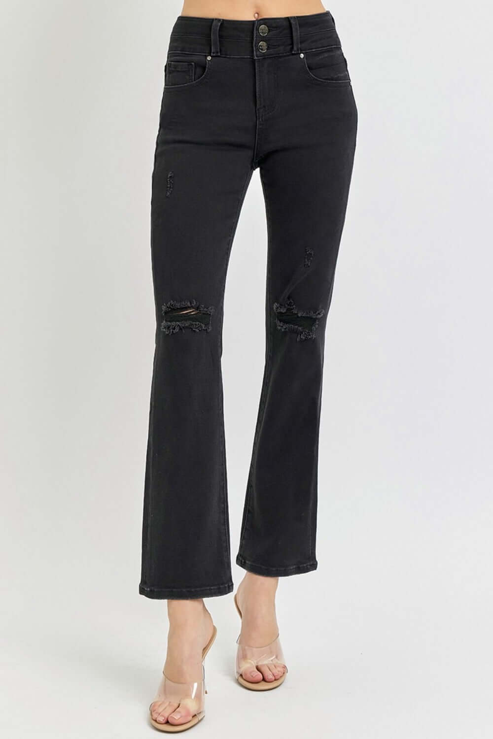 Black high-rise wide waistband ankle bootcut jeans with distressed detailing, styled with clear heels for a modern look.