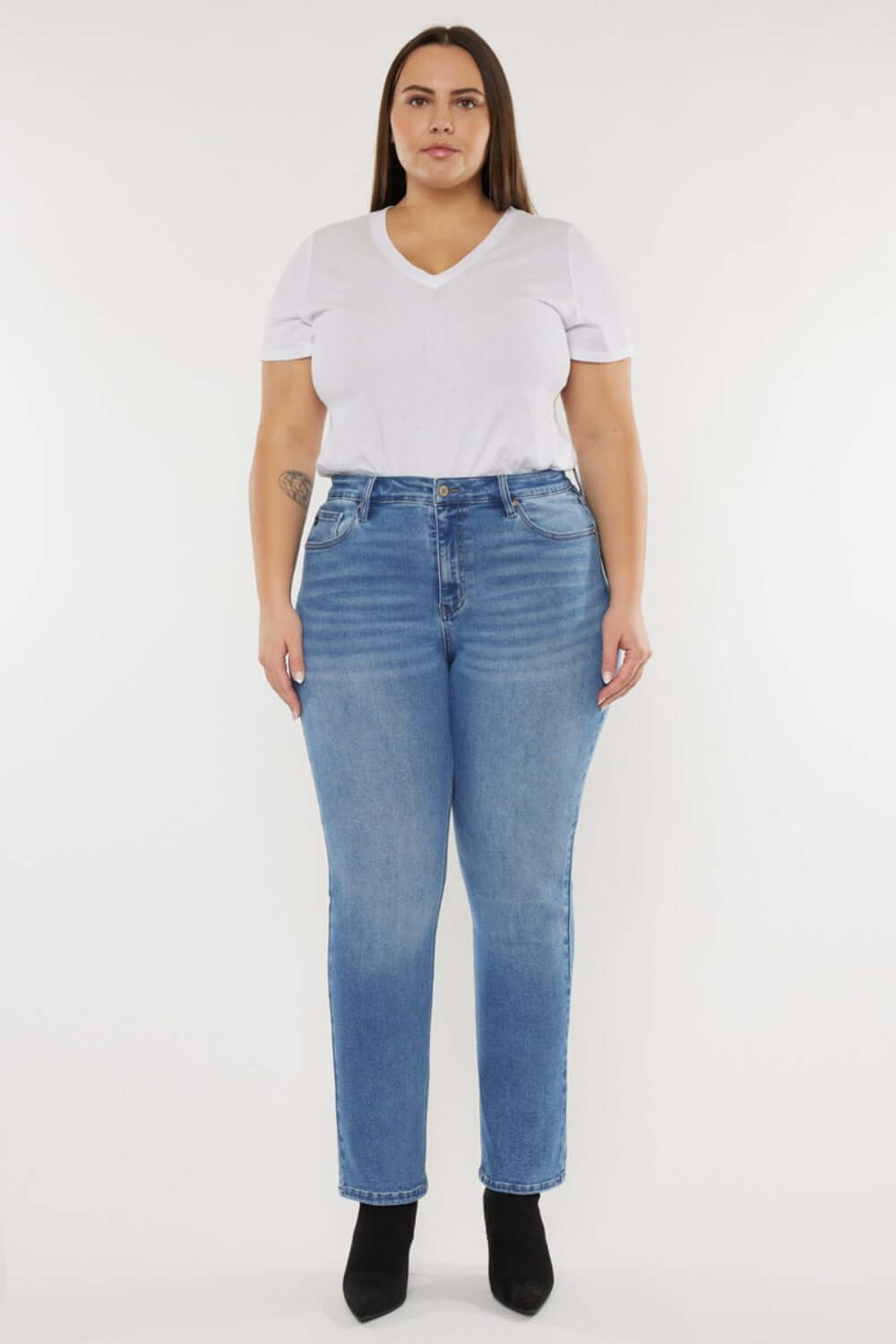 Woman wearing Cat's Whiskers High Waist Jeans with vintage detailing, paired with a white top and black boots.