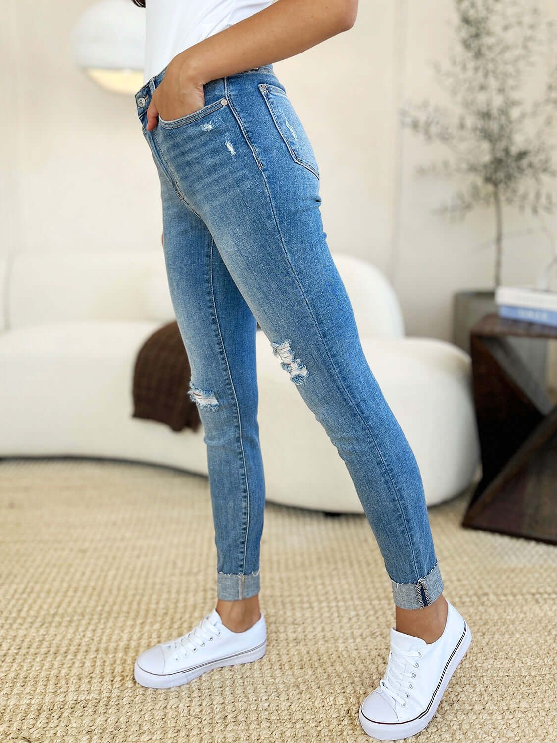 Side view of model wearing Mid Rise Destroy & Cuff Skinny Jeans by Judy Blue Jeans, showcasing distressed detailing and cuffed hem.