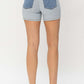 Back view of Judy Blue Jeans color block denim shorts, showcasing contrasting pockets, on a model wearing white sneakers