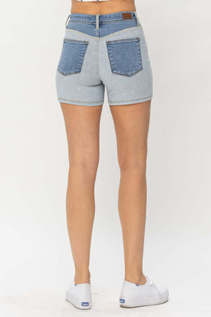 Back view of Judy Blue Jeans color block denim shorts, showcasing contrasting pockets, on a model wearing white sneakers