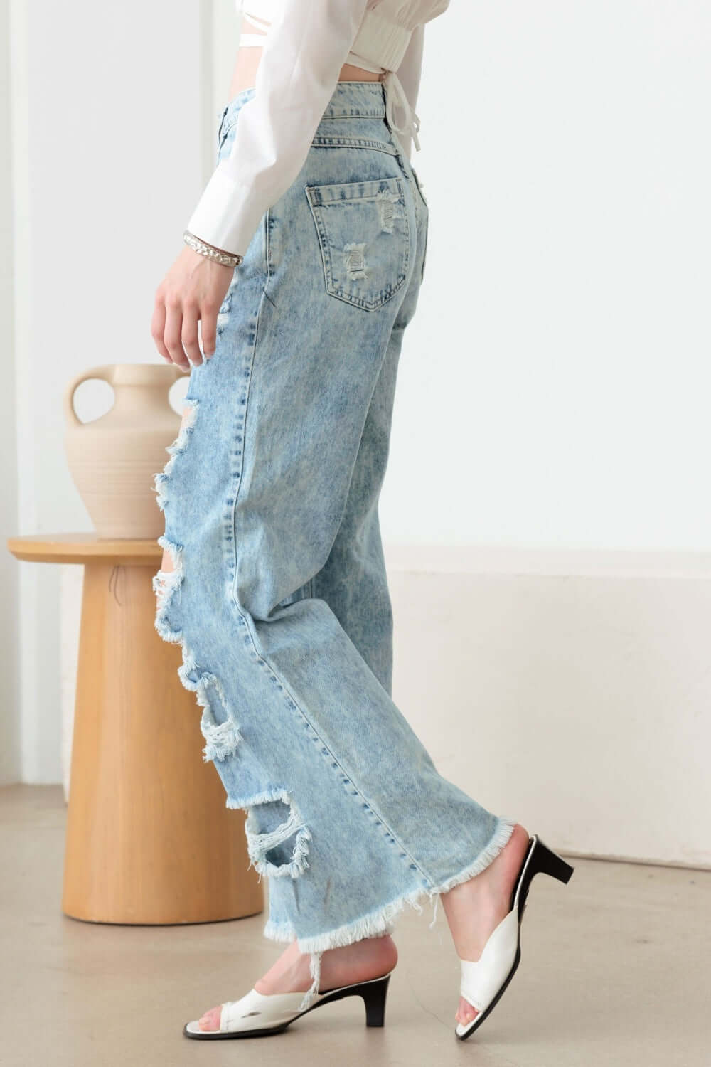 Woman wearing Distressed Frayed Hem Flare Jeans with ripped edges, showcasing trendy style and classic 5 pockets.