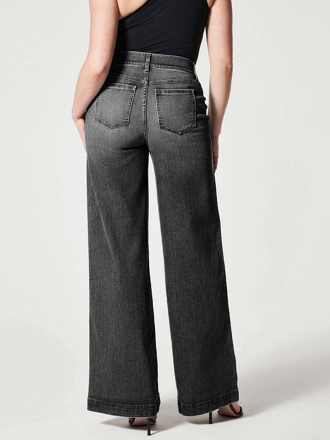 Woman modeling chic wide leg long jeans in solid gray, showcasing back view with moderate stretch fit and basic style.