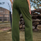 Woman wearing Bella Road High Waist Cargo Straight Jeans in green, showing back pocket detail and outdoor scenery.