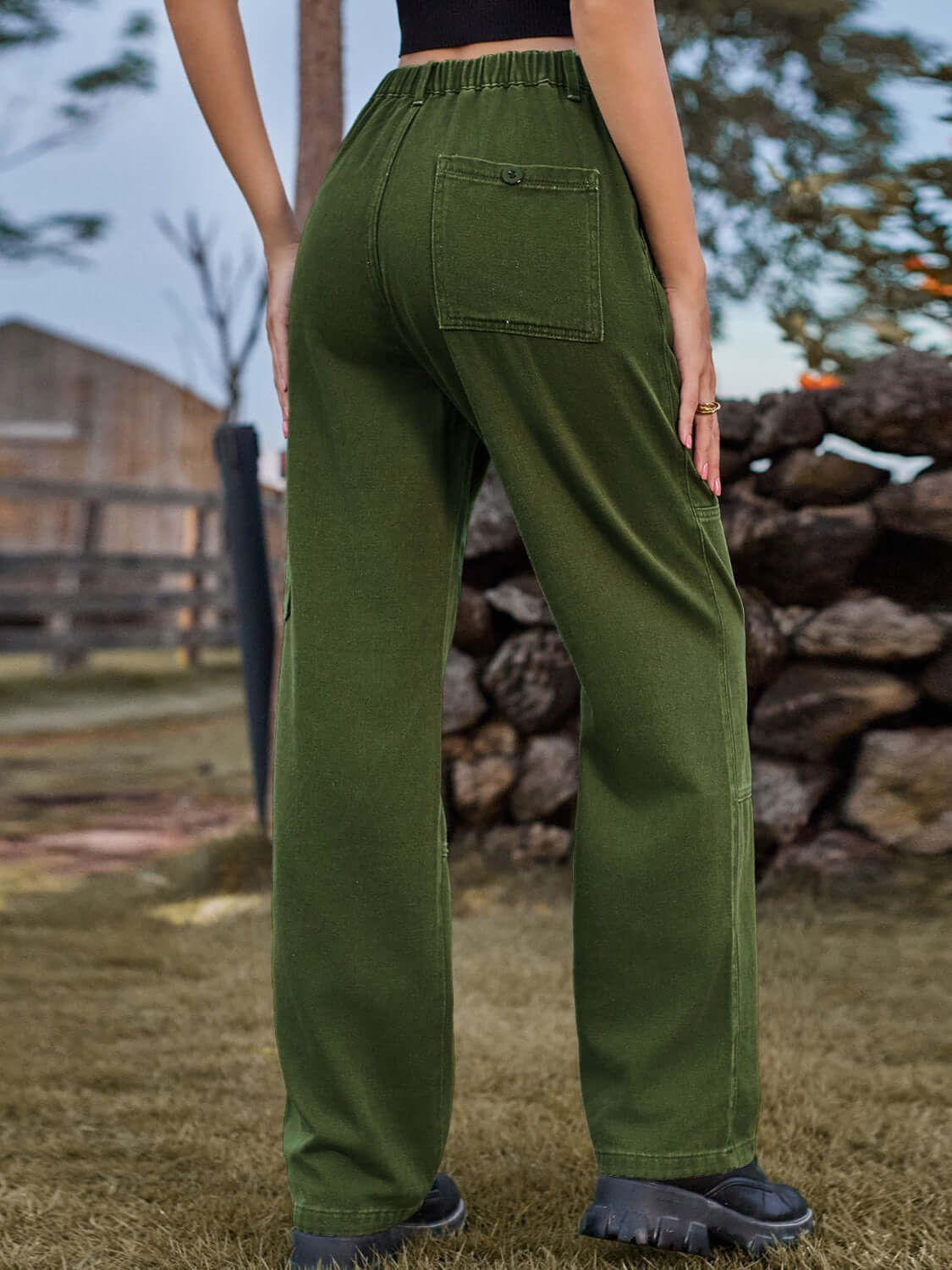 Woman wearing Bella Road High Waist Cargo Straight Jeans in green, showing back pocket detail and outdoor scenery.