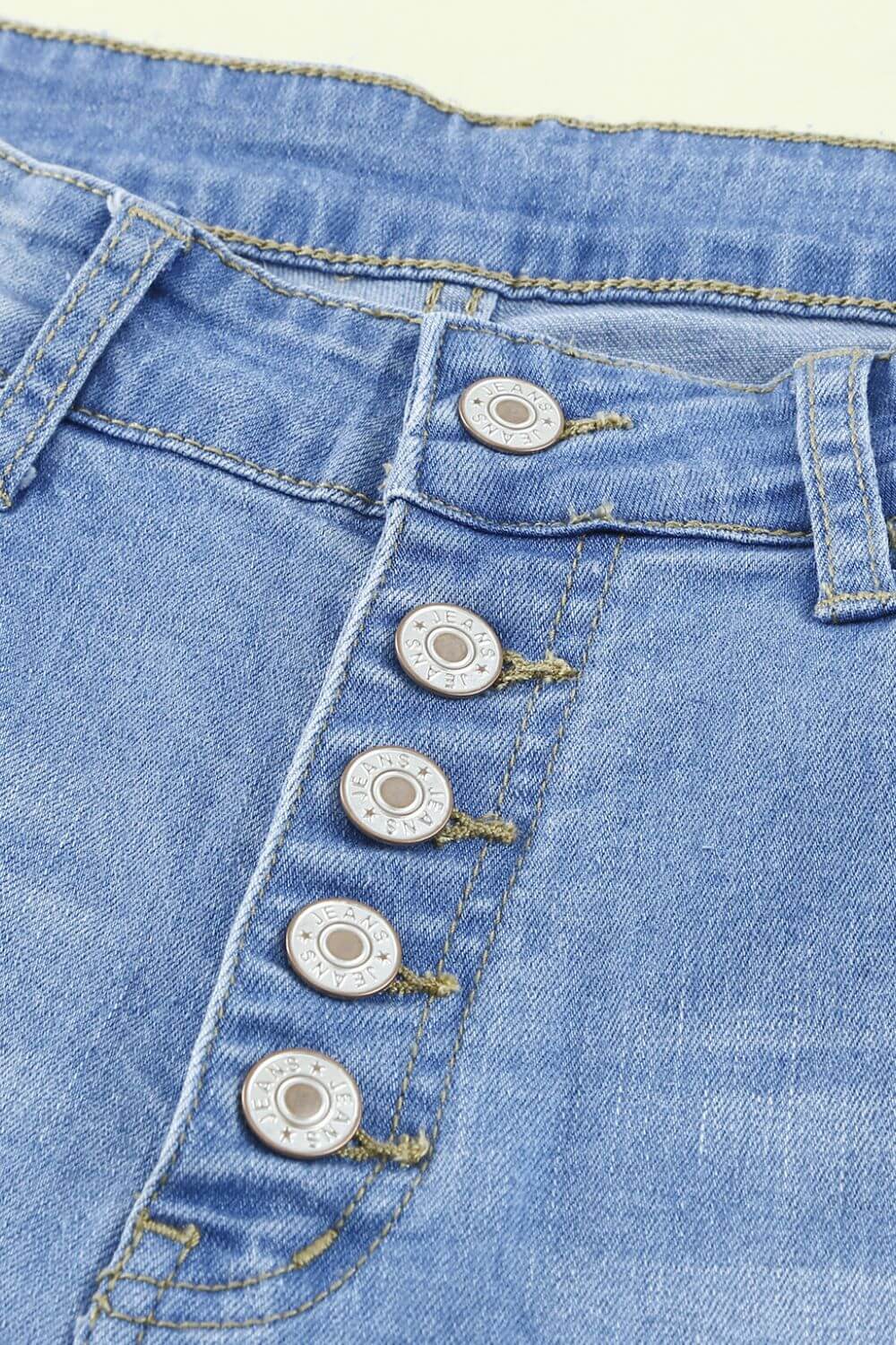 Close-up of Bella Road Button-Fly Distressed Raw Hem Flare Jeans waist and button-fly detailing.