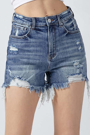 Woman wearing high rise distressed denim shorts with frayed hems by Risen Jeans, perfect for a stylish summer look.