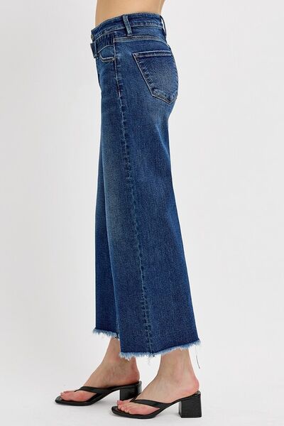 Wide leg raw hem jeans with attached buckle, showcasing a trendy and relaxed fit, paired with stylish heels.