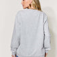 Woman wearing gray letter graphic long sleeve sweatshirt with blue jeans, shown from the back.