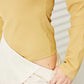 Woman wearing a mustard ribbed bodysuit paired with a light beige skirt, highlighting the soft and stretchy fabric.