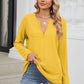 Woman wearing Bella Road Waffle-Knit Notched Long Sleeve T-Shirt in yellow, paired with blue jeans, standing on steps.