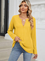 Woman wearing Bella Road Waffle-Knit Notched Long Sleeve T-Shirt in yellow, paired with blue jeans, standing on steps.