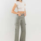 Woman wearing '90s super high rise loose cargo jeans with ultra-high waist, paired with a white crop top and heels.