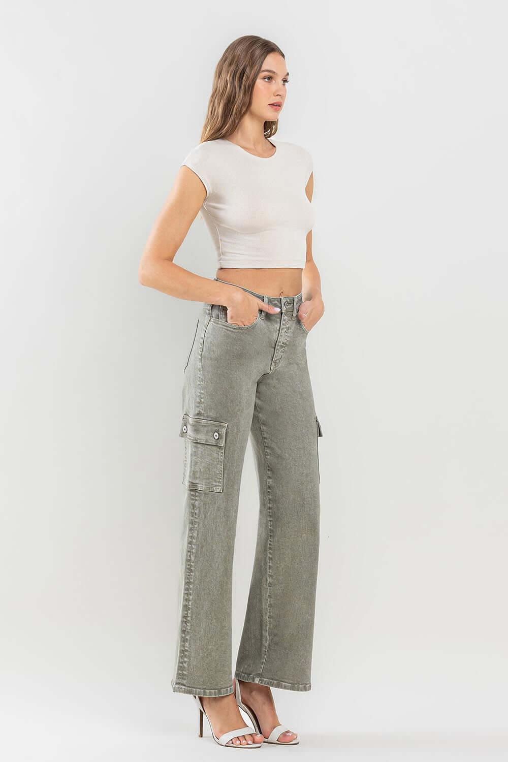 Woman wearing '90s super high rise loose cargo jeans with ultra-high waist, paired with a white crop top and heels.