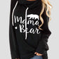 Woman wearing a black hoodie with white drawstring and "Mama Bear" letter graphic design.