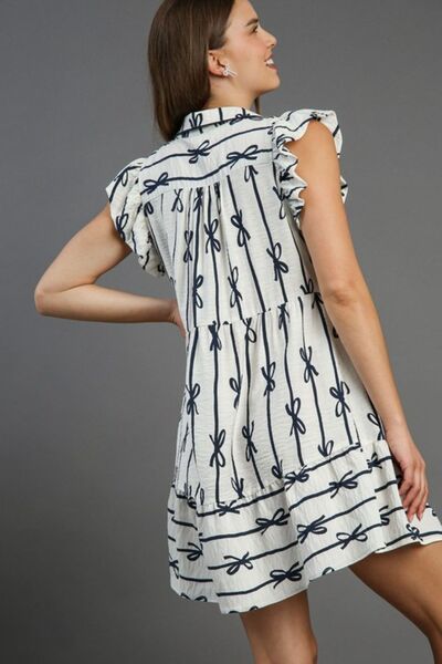 Model showcasing the Umgee Plus Size Ribbon Collared Mini A-Line Dress with ruffled sleeves and bow pattern.