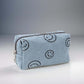 Small blue corduroy cosmetic pouch with cheerful embroidered smiley faces, perfect for makeup organization on-the-go.