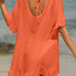 Woman wearing a coral tied ruffled half sleeve cover-up on the beach, featuring sheer material with no stretch, composed of 65% cotton and 35% polyester.