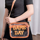 Woman holding a Zenana GAME DAY Transparent Crossbody Bag with glittered trim and adjustable strap, perfect for stadium use.