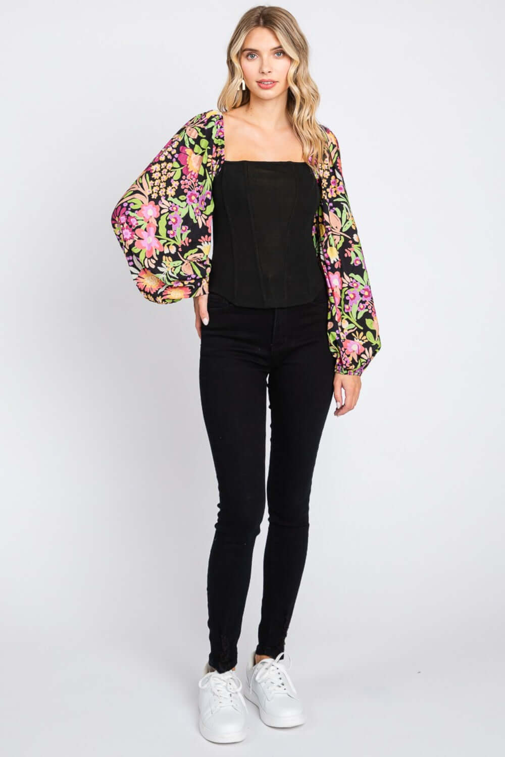 Woman wearing Floral Balloon Sleeve Blouse in black with colorful floral print, standing against a white background.