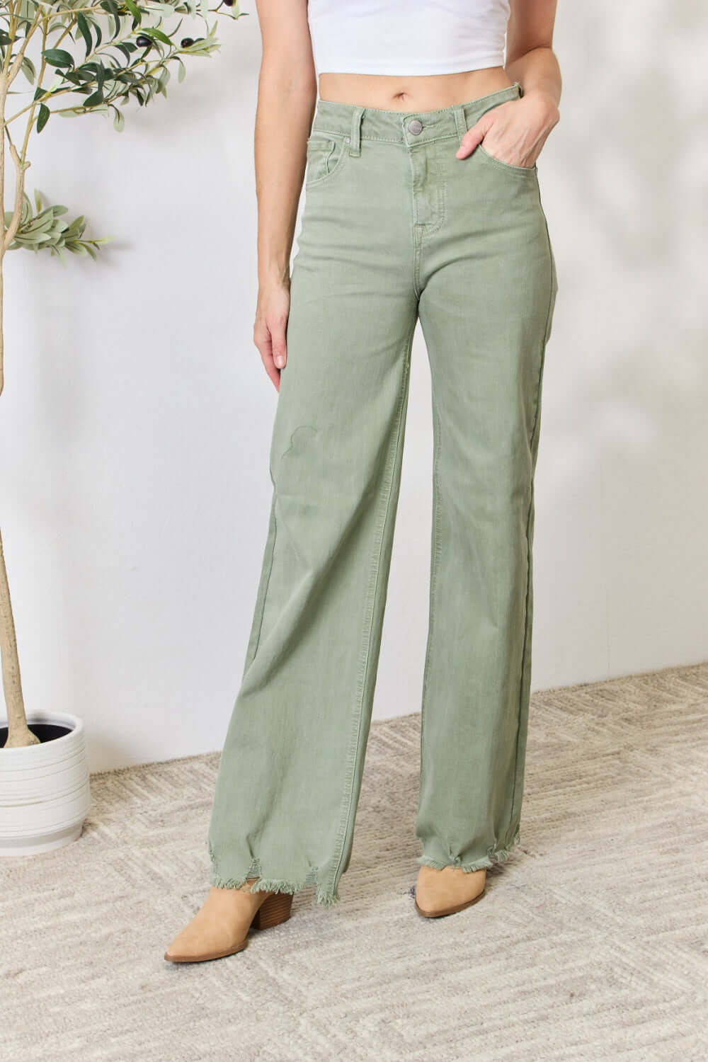 Woman modeling green raw hem wide-leg Risen Jeans with a high-waisted fit, pocket detail, and slightly stretchy fabric.